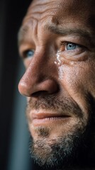 Obraz premium Close up portrait of a mature bearded man with blue eyes shedding a single tear