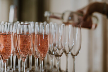 Glasses with pink champagne or non alcoholic fizz being poured in the background with copy space © zoerae28