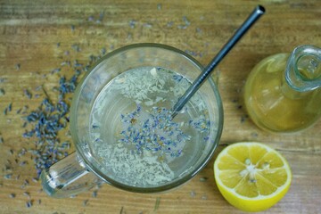 A refreshing herbal drink presented in a clear glass mug, garnished with lavender buds and...