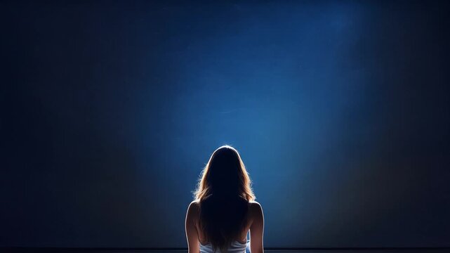 Silhouette of a young woman sitting with her back to the camera, over her head are swirly lines, which are disappearing, concept of overthinking and calming