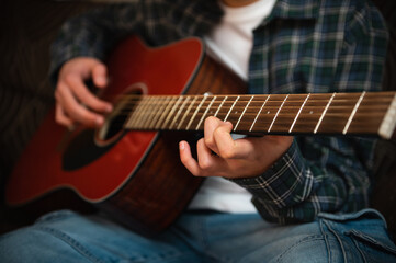 Fototapeta premium Teenage Boy Playing Acoustic Guitar At Home Strumming Music In Casual Cozy Interior