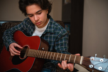 Obraz premium Teenage Boy Playing Acoustic Guitar At Home In Cozy Casual Setting