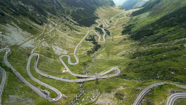 Aerial forward flight over Transfagarasan mountain road winding through Fagaras Mountains, scenic serpentine in Romania