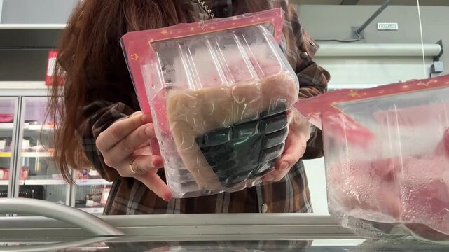 A close-up of packaged meat in a supermarket. A woman buys packaged pork from a store shelf.