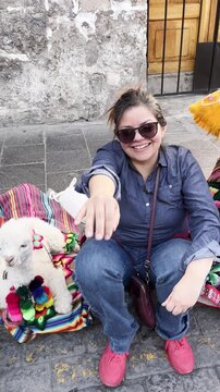 POV young woman petting a cute baby alpaca in Arequipa