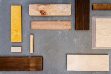 Flat lay of various wood and plywood pieces on concrete texture. Carpentry background.