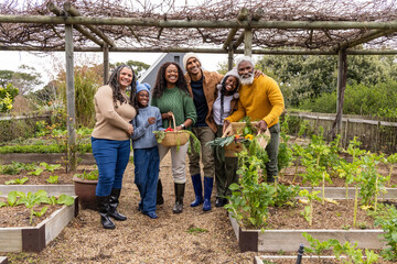 Multigenerational African American family holding baskets in backyard garden wearing boots