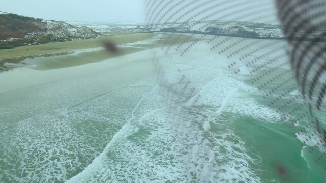 Shoreline appearing and disappearing under patterned mesh moving by wind, camera tracking coastline