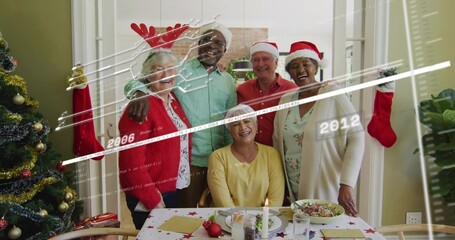 Gathering five seniors wearing Santa hats and reindeer antlers at home table with tree, stockings © vectorfusionart