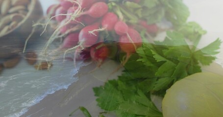 Naklejka premium Overlaying bunch of red radishes with parsley on countertop, shoreline waves and pale bulb showing