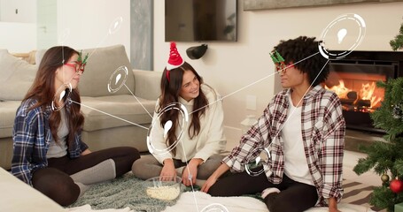 Fototapeta premium Passing clear bowl popcorn women sitting on living room rug, wearing holiday glasses and Santa band