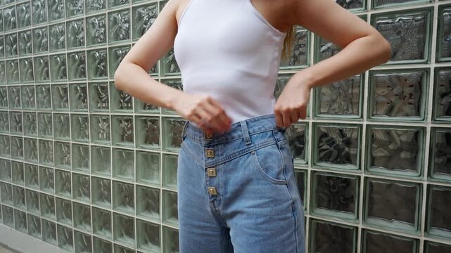 Model demonstrates how to wear high-waisted denim jeans with buttons in an urban setting