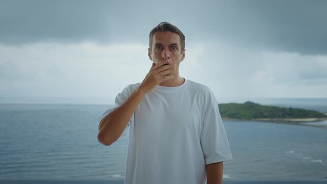 Surprised man reacts to unexpected news by removing sunglasses on seaside balcony with ocean view showing shock surprise and surprise emotion during summer vacation moment. Emotional reaction concept
