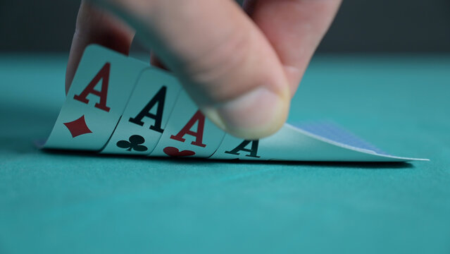 Close-up image of a poker hand revealing four aces on a green casino table. Dramatic gambling scene symbolizing luck, winning, risk, strategy, and success. Focus on playing card detail and tension 