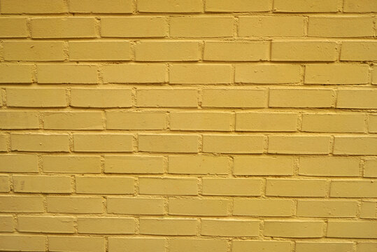 Seamless background of a bright yellow painted brick wall texture.