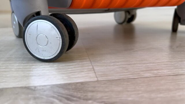 Suitcase with spinner wheels rolling on a wooden floor