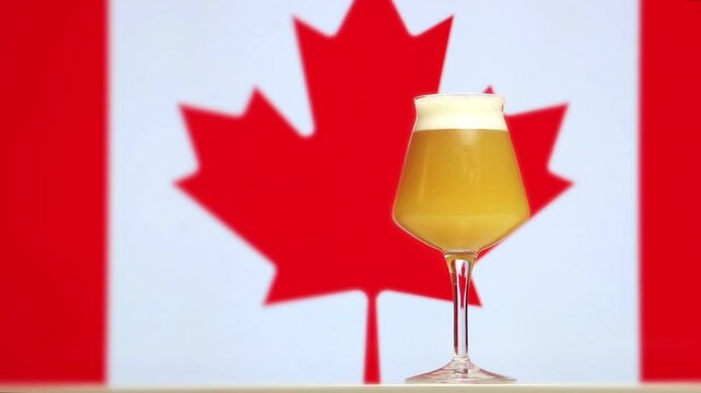 A hazy craft beer in a Teku glass with a Canadian maple leaf flag background.