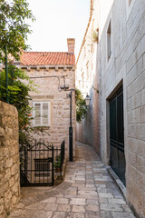 Fototapeta premium Scenic narrow stone street and medieval limestone walls in Dubrovnik Old Town at sunrise, Croatia. Historic Mediterranean architecture, ancient fortress view with Adriatic sea on background.