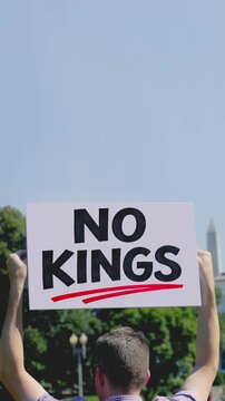 Vertical protester holds a &ldquo;NO KINGS&rdquo; sign in front of the White House, referencing concerns about presidential overreach. A bold political expression of democracy