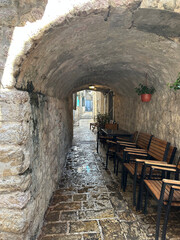 Narrow stone alley with arched ceiling and wooden chairs in old town of Budva Montenegro historic architecture travel destination