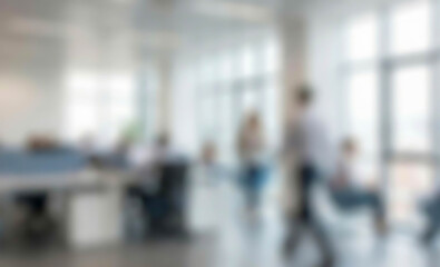 Obraz premium Blurred view of a modern office scene with employees engaged in work. The image shows several individuals at desks, collaborating in a bright, spacious environment.