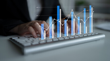Business professional analyzes financial data with various graphs and charts while typing on a...