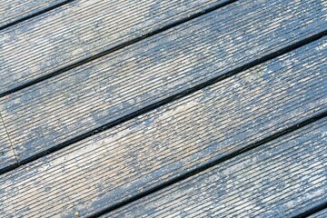 Tekstura starych, drewnianych desek tarasowych z resztkami niebieskiej farby. Zbliżenie na ryflowaną powierzchnię drewna, idealne jako tło do projektów i wizualizacji. © Henryk Niestrój
