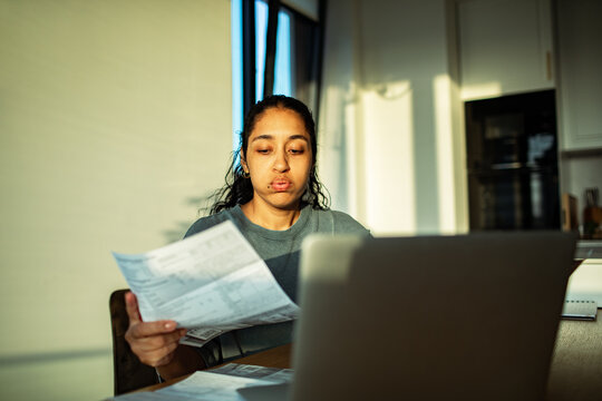 Young woman reviewing bills on laptop at home