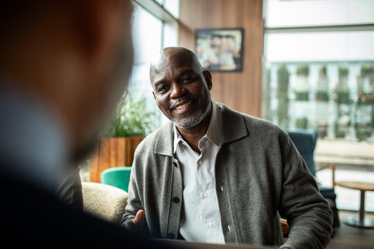 Smiling mature man meeting with colleague in cafe lounge
