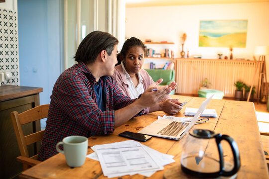 Couple discussing bills at home kitchen table