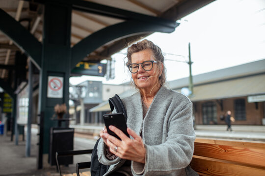Senior woman using smartphone at train station platform