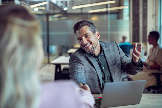 Smiling businessman shaking hands during job interview in modern office