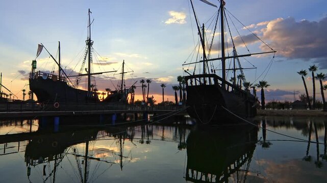 Historic replicas of the Pinta, Nina, and Santa Maria caravels at Muelle de las Carabelas, Huelva, Spain, during a colorful sunset. Ideal for travel and history content