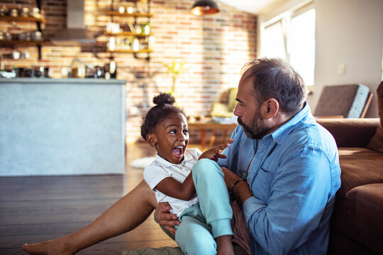 Father tickling daughter on living room floor