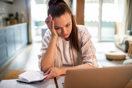 Stressed young woman working from home on laptop