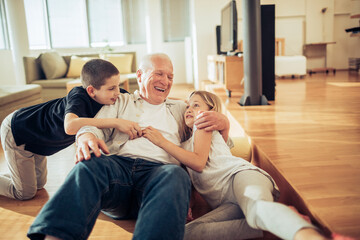 Fototapeta premium Grandfather playing with grandchildren on living room floor