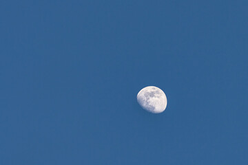 Minimalist scene showing bright moon against blue sky with subtle shadows and gradients