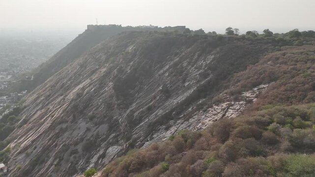 Drone flying over rocky hills toward Nahargarh Fort in Jaipur Rajasthan India