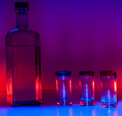 Bottle and tequila glasses with colorful lighting 23