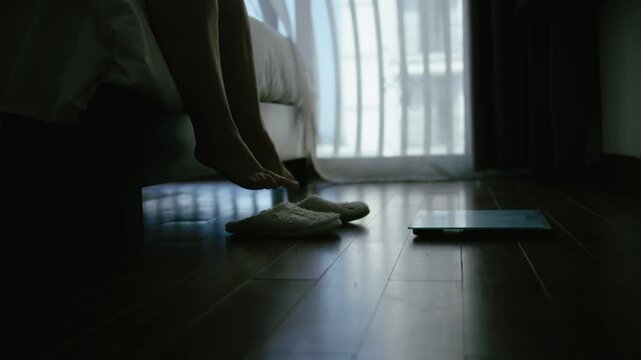 Plus Size Woman Stepping onto Scale in Bedroom at Night