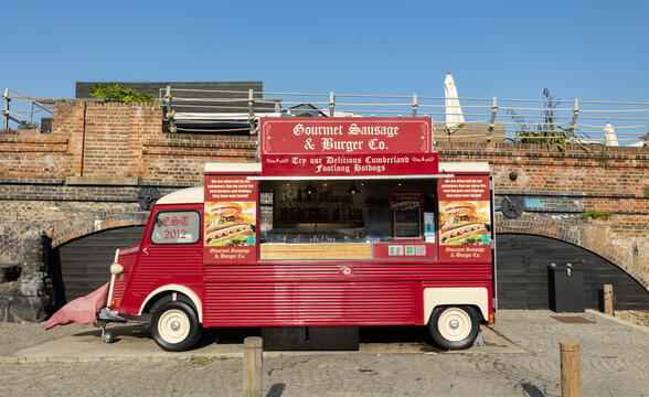 Folkestone, Kent ,uk August 1,  2023 Vintage Red Gourmet Sausage & Burger Food Truck Parked by Brick Archway on Sunny Day