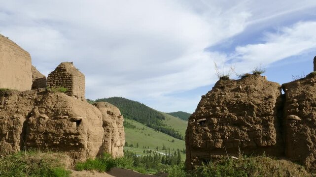 The stone ruins of an ancient Buddhist monastery on the background of a forested mountain and a blue cloudy sky. Monastery of Manjusri near Ulan Bator, Mongolia. Summer sunny day.