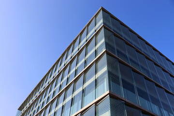 Modern glass office building corner against blue sky, corporate architecture background