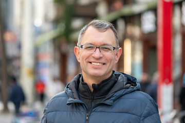 Obraz premium Portrait of adult man in urban environment with pedestrians background