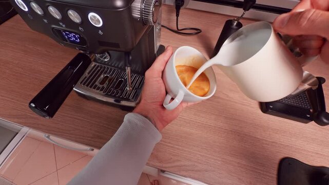 Top Down View of Milk Being Poured Into Espresso Cup Creating Swirling Pattern Before Latte Art Formation Showing Preparation Stage and Control of Microfoam Texture