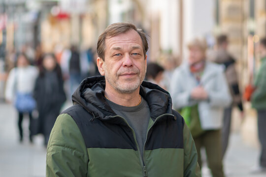 55 year old man standing on European city street among pedestrians daytime