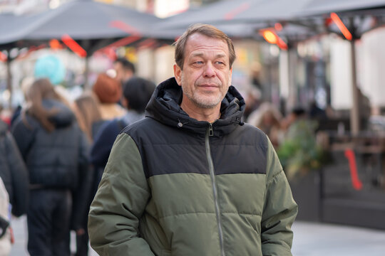 55 year old man walking along European city street in city center
