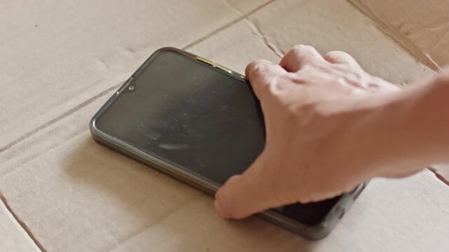 Someone Hand Picking Up Smartphone on Cardboard, Motion of Taking Modern Gadget from Rough Surface, Technology Dependency and Fast Communication Access Concept
