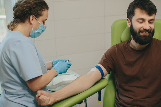 Nurse drawing blood from male patient arm