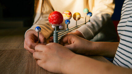 Fototapeta premium Children assembling a solar system model, learning about planets and space exploration
